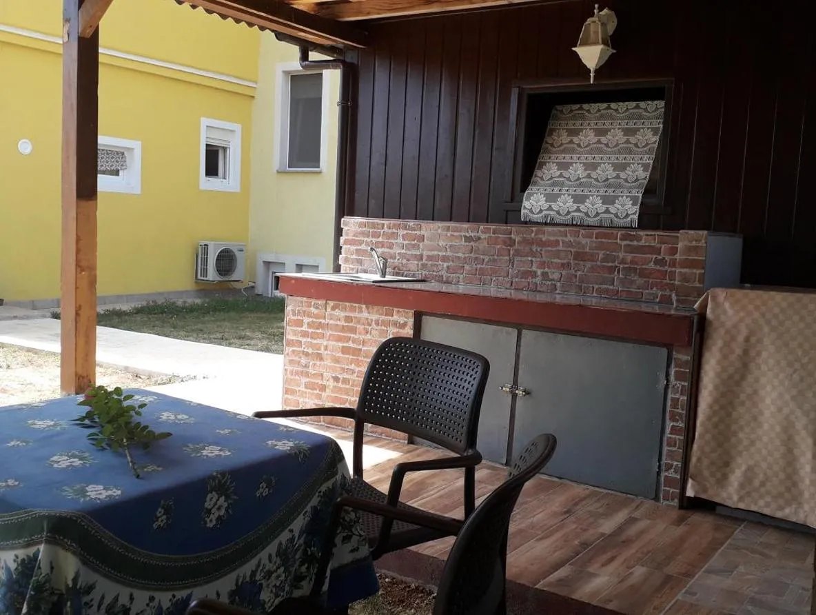 Natkrivena terasa s ljetnom kuhinjom i stolom za blagovanje na otvorenom